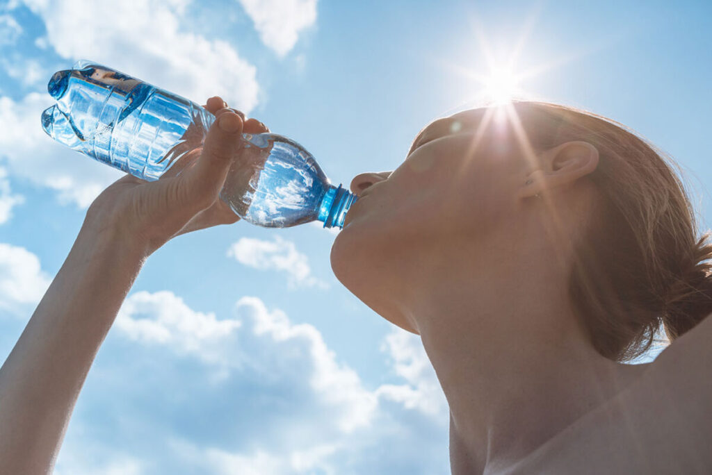 太陽の下でシリカ水を飲む女性