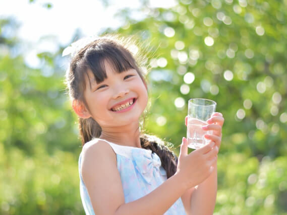 水の入ったコップをもつ笑顔の女の子