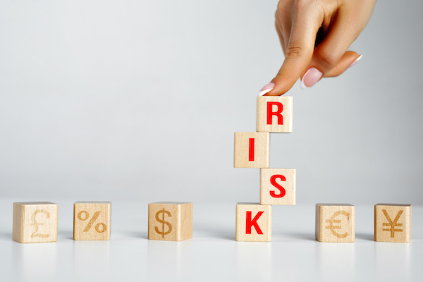Wooden cubes that create an unstable structure and the word risk