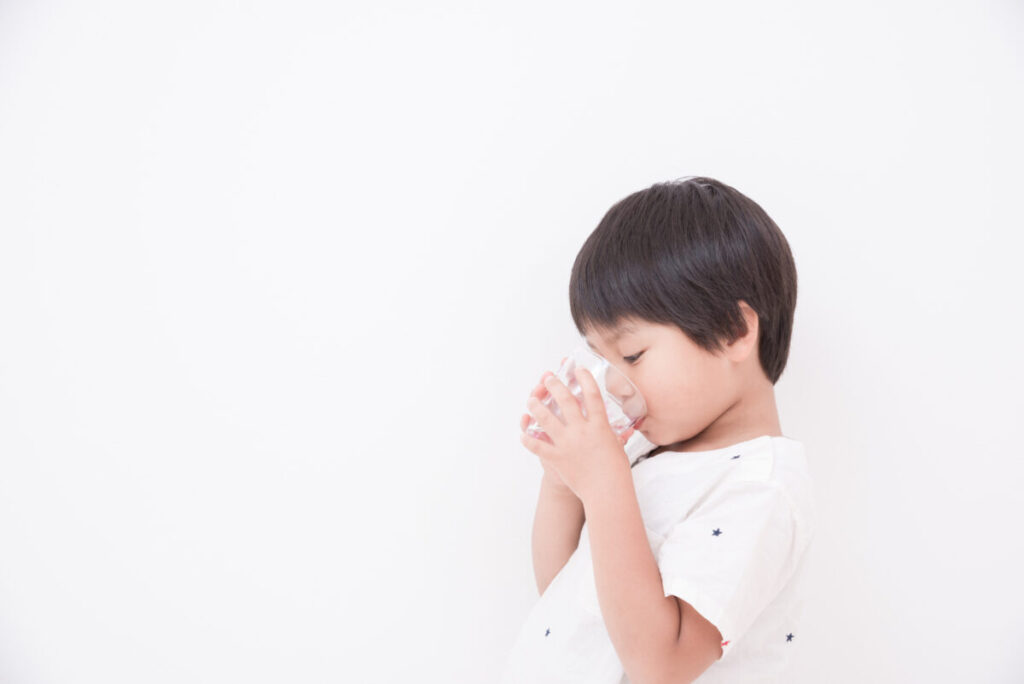 コップで水を飲む男の子