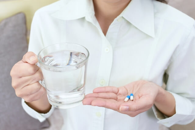 水で薬を飲む女性”